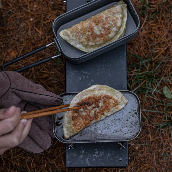 Aluminium camp cooking pot with food on ground