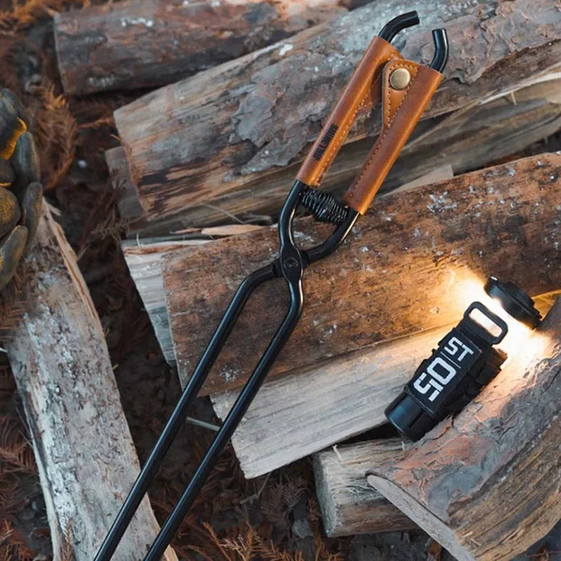 Camping fire poker with wooden handle resting on logs