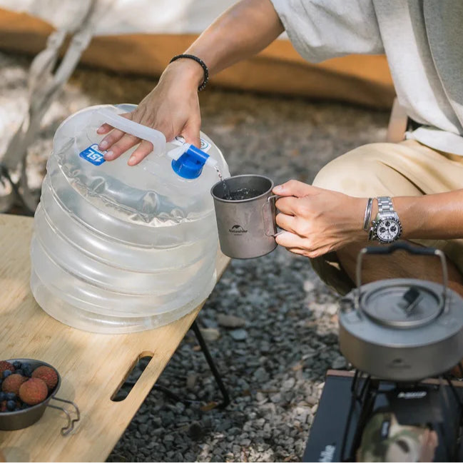 Collapsible water bucket pouring water at campsite