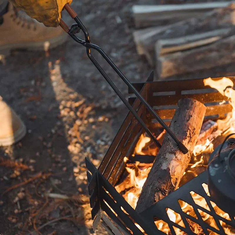Metal fire poker adjusting logs over campfire