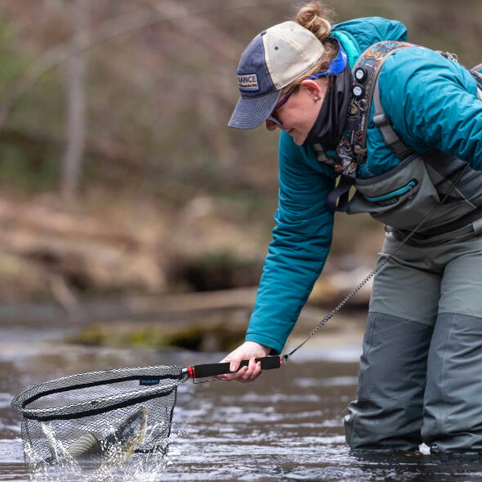 Angler using foldable landing net with EVA handle while wading in stream