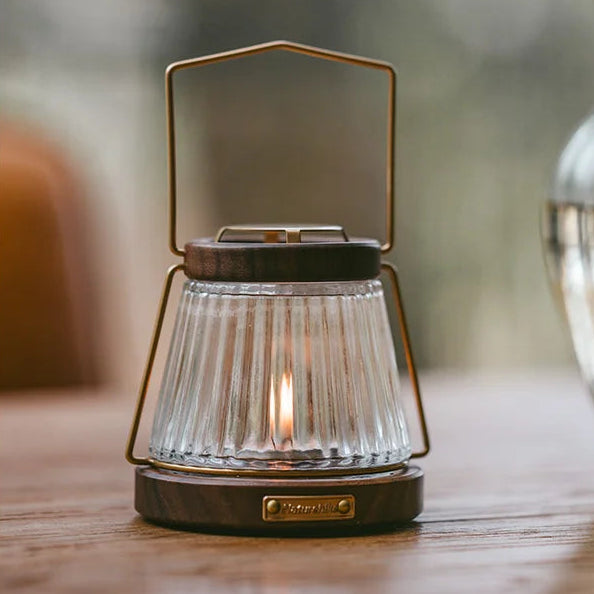 NATUREHIKE retro candle lantern made of walnut, glass, and iron creating warm ambient light on table surface