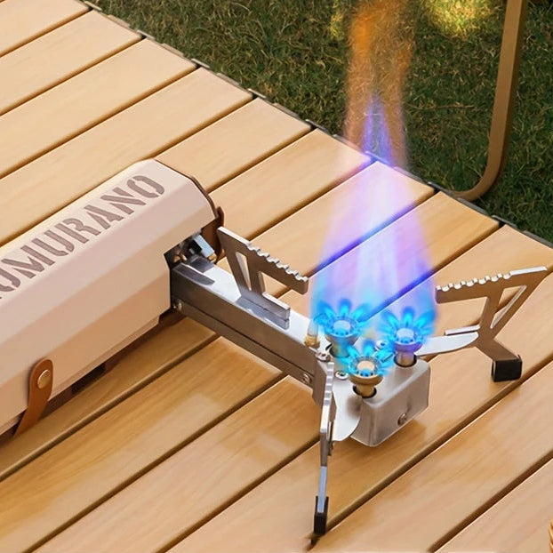 Portable folding cassette gas stove with blue flame for outdoor cooking and camping use on wooden table