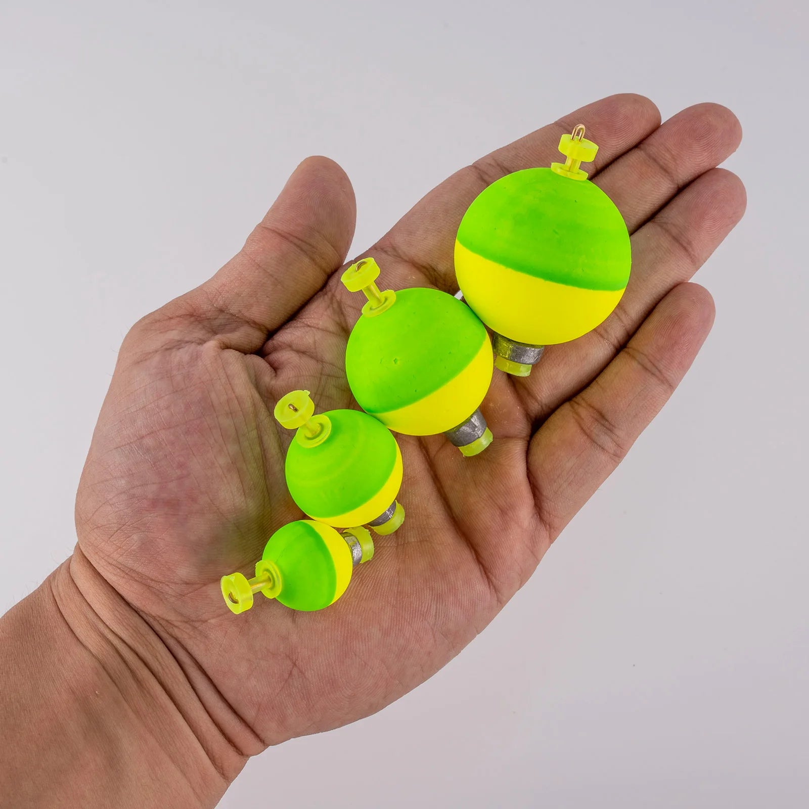 Hand holding snap-on fishing bobbers showing compact float sizes