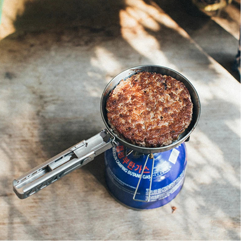 Titanium frying pan cooking on portable camping gas stove