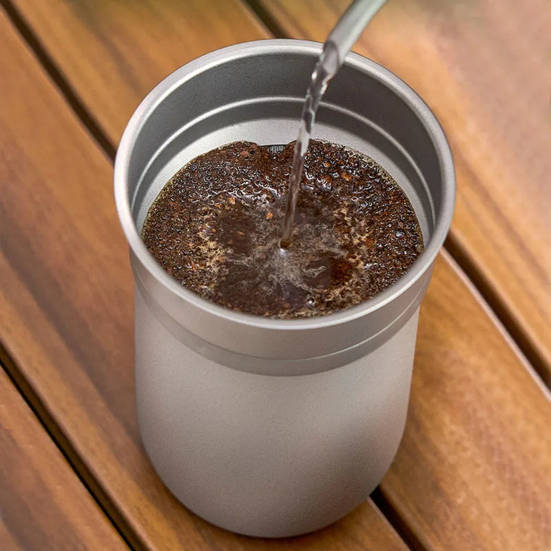 Titanium coffee mug and reusable filter brewing fresh coffee, ideal for travel or minimalist brewing setups