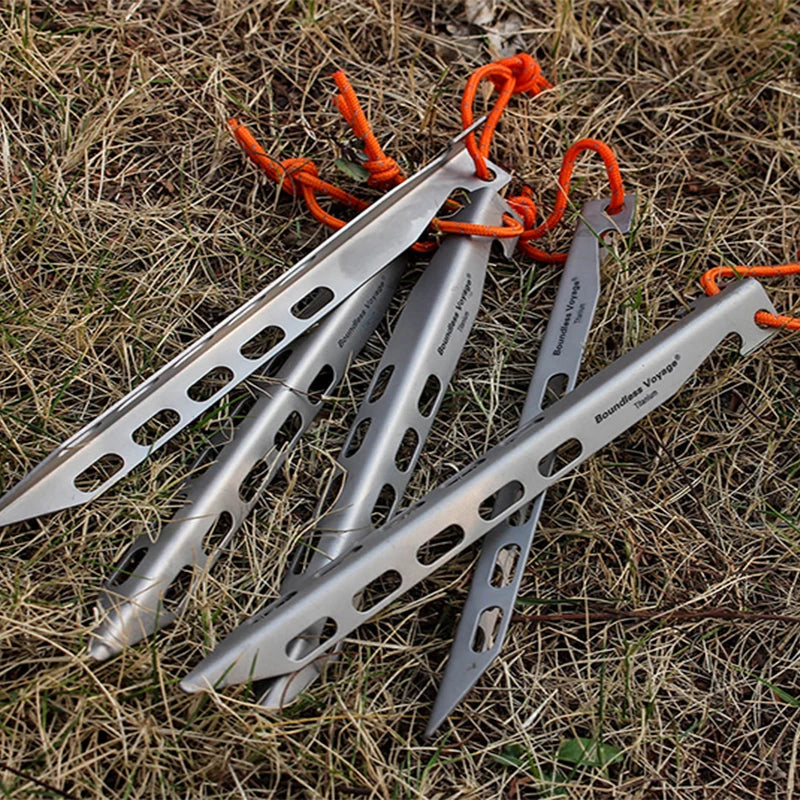 Titanium V shape tent stakes with orange cords on grass