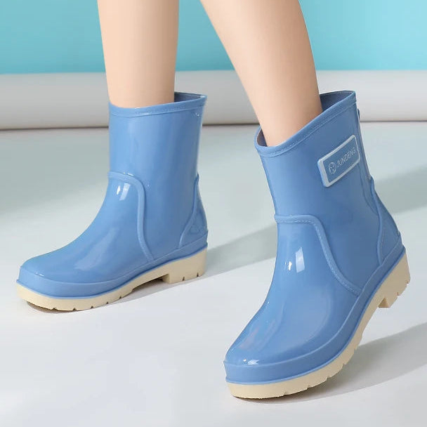 Blue women’s ankle gumboots worn on legs against studio background