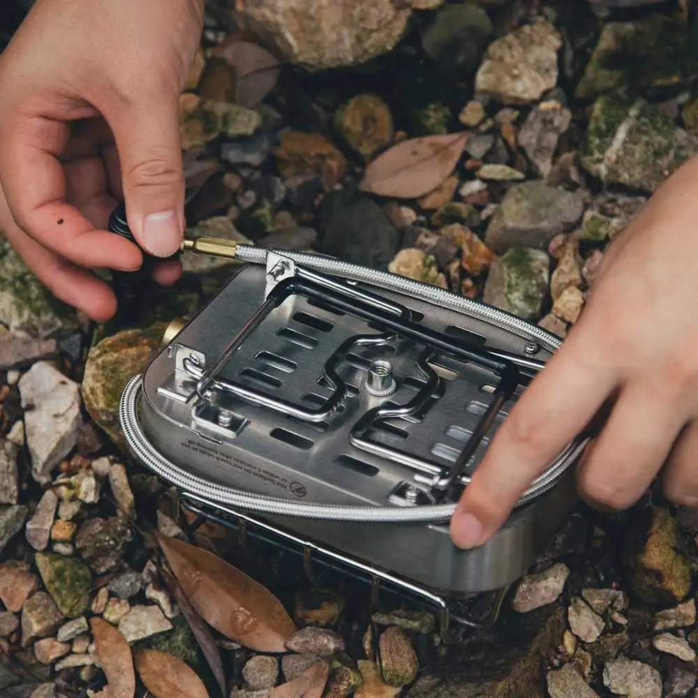 Camper assembling foldable infrared gas stove in outdoor setting showing compact camping design