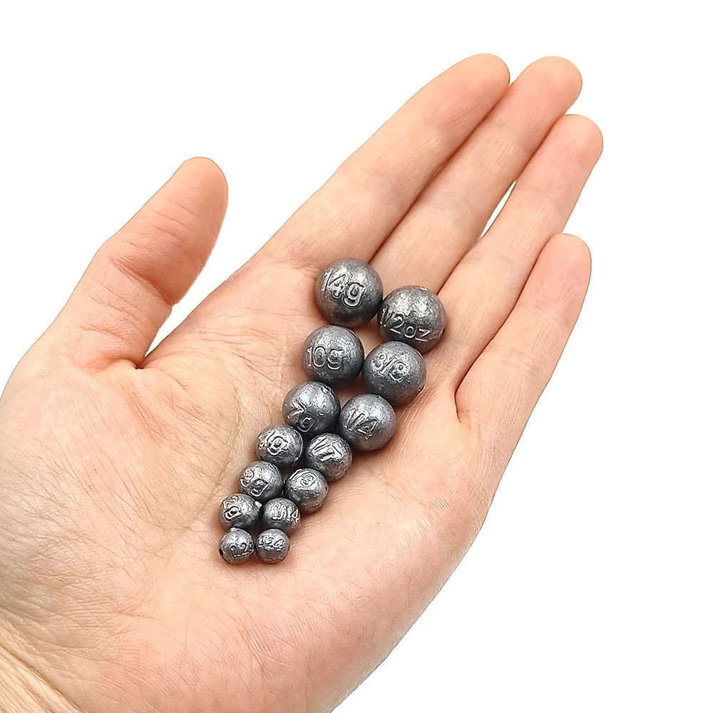 Mixed size ball fishing sinkers shown in hand for size comparison