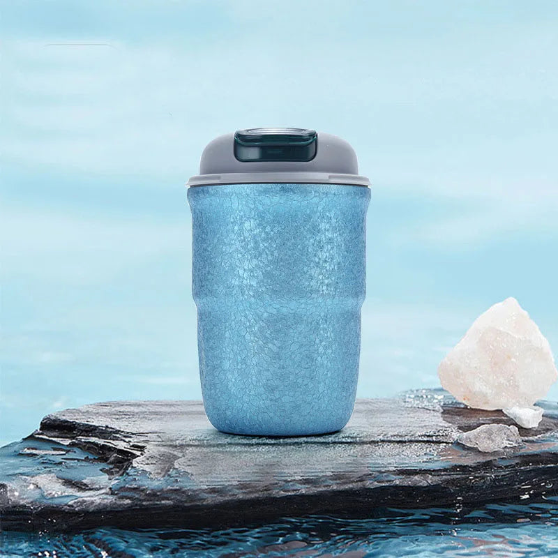 Blue titanium belly flask with leakproof lid placed on rock surface ideal for hiking, fishing, and camping