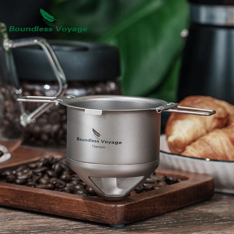 Foldable titanium coffee filter on a camping table with coffee beans and mug for outdoor brewing convenience