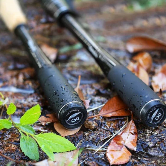 Close-up of TSURINOYA rod handles with carbon monocoque grips and cork sections resting on damp forest ground