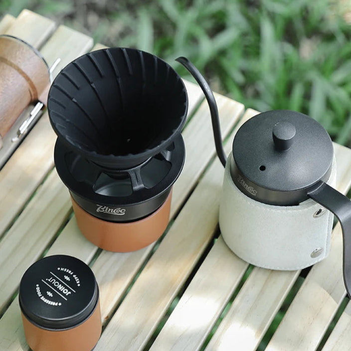 Coffee dripper and kettle set arranged outdoors on camp table for hand pour brewing