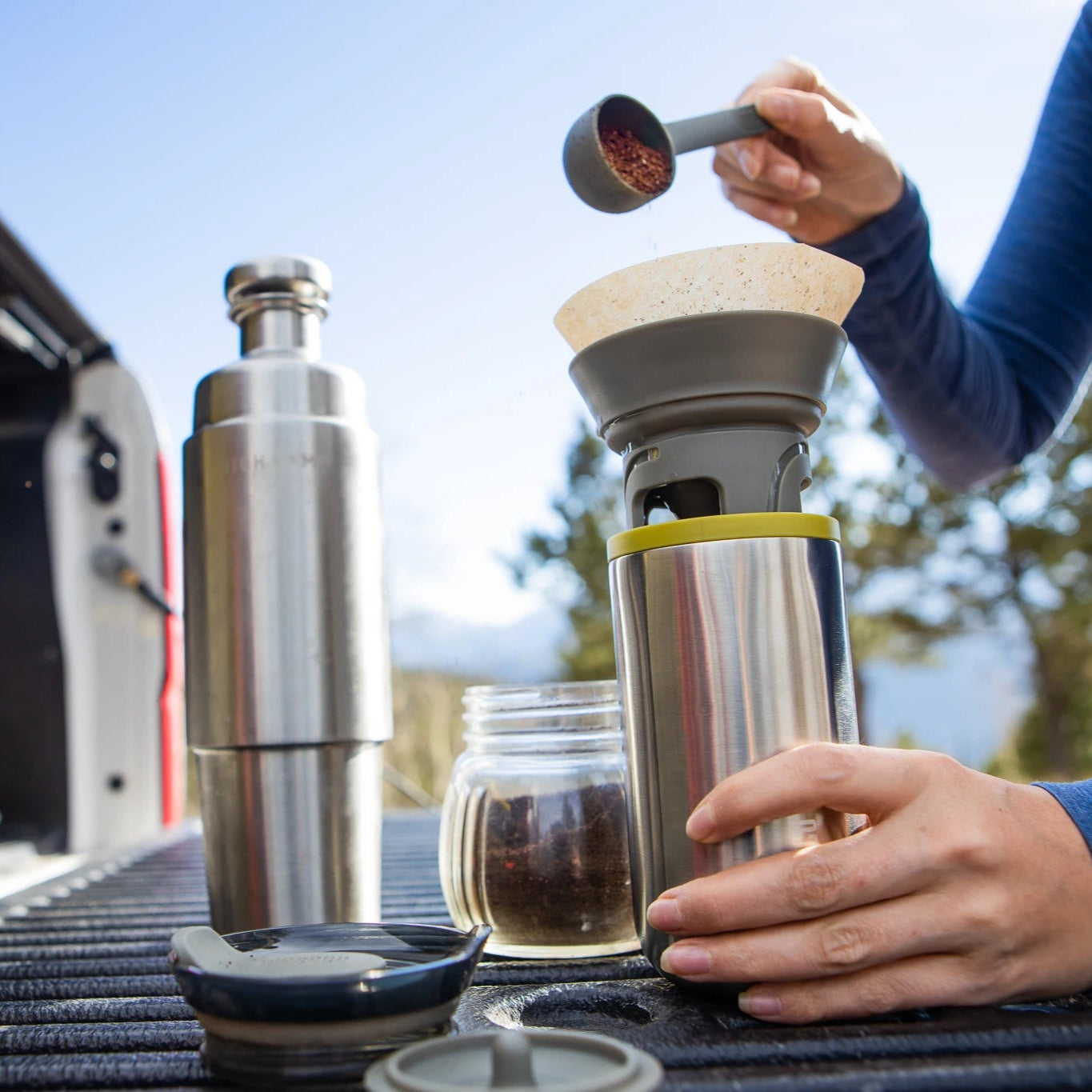 WACACO Cuppamoka used for pour-over coffee beside thermos during camping or outdoor trip
