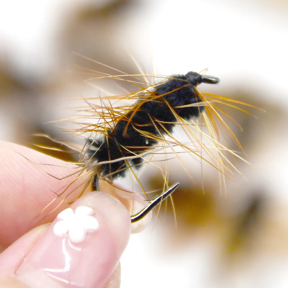 Gold head worm trout fly held between fingers