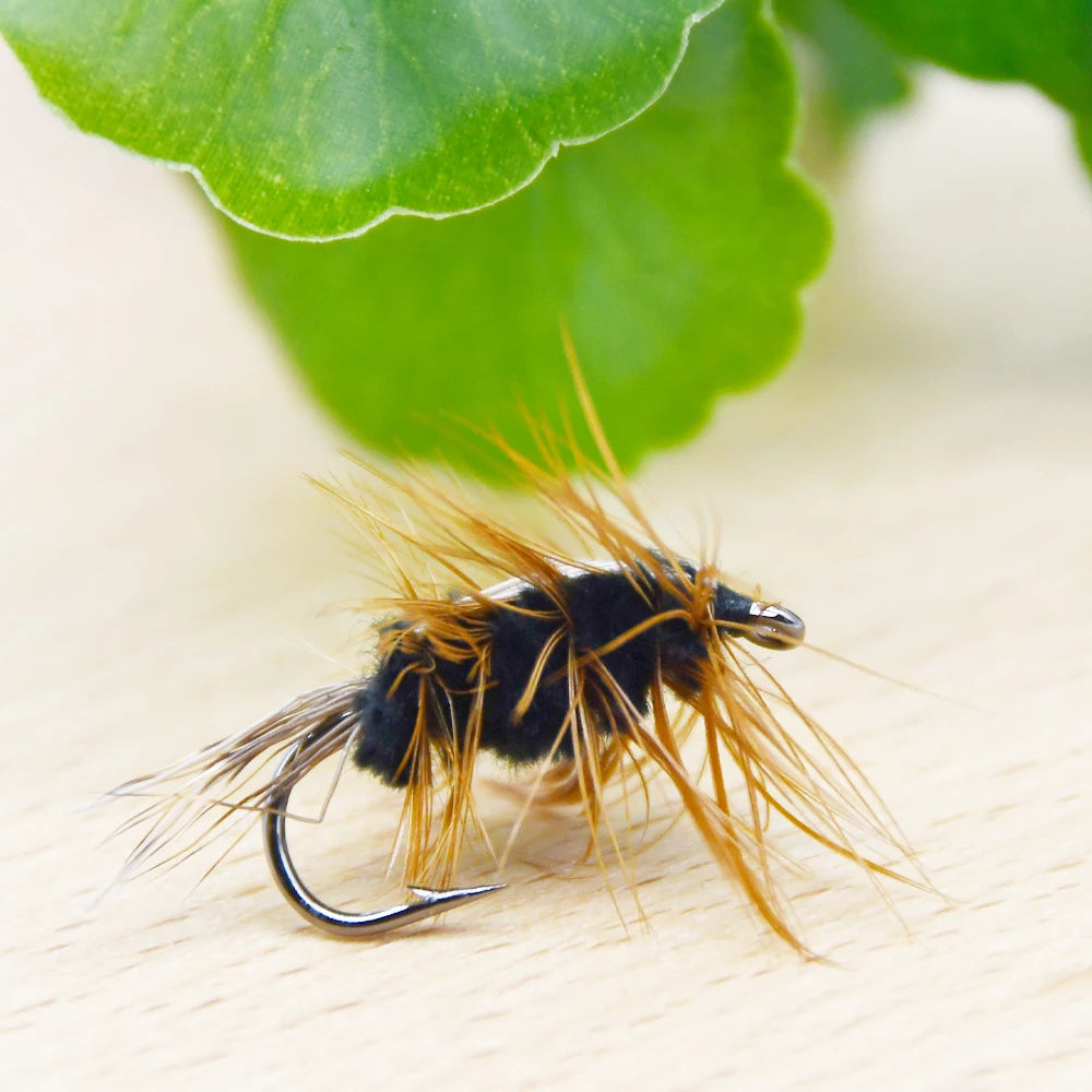 Gold head worm trout fly resting on green leaf