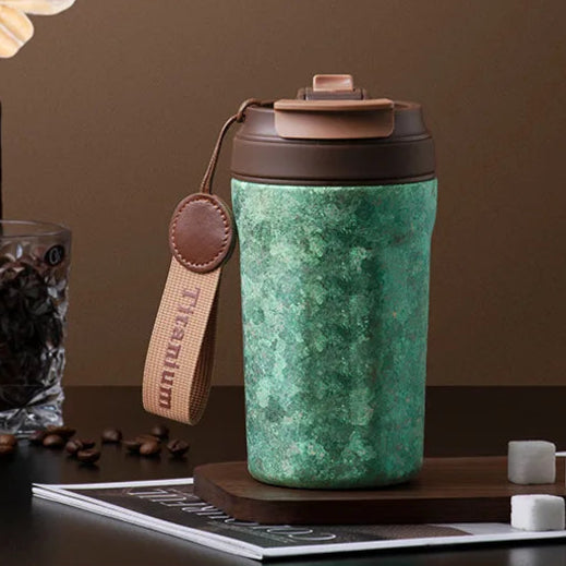 Green titanium thermos flask with lifting strap and textured surface, built for outdoor or everyday use