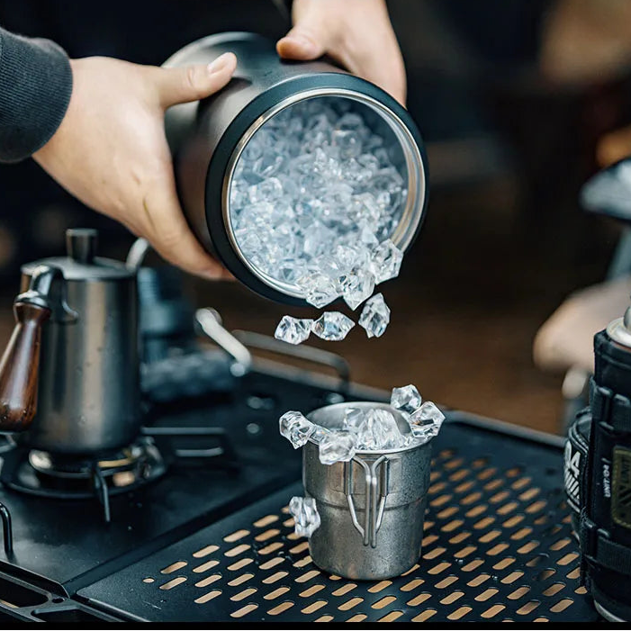 Stainless steel ice bucket with ice cubes being poured
