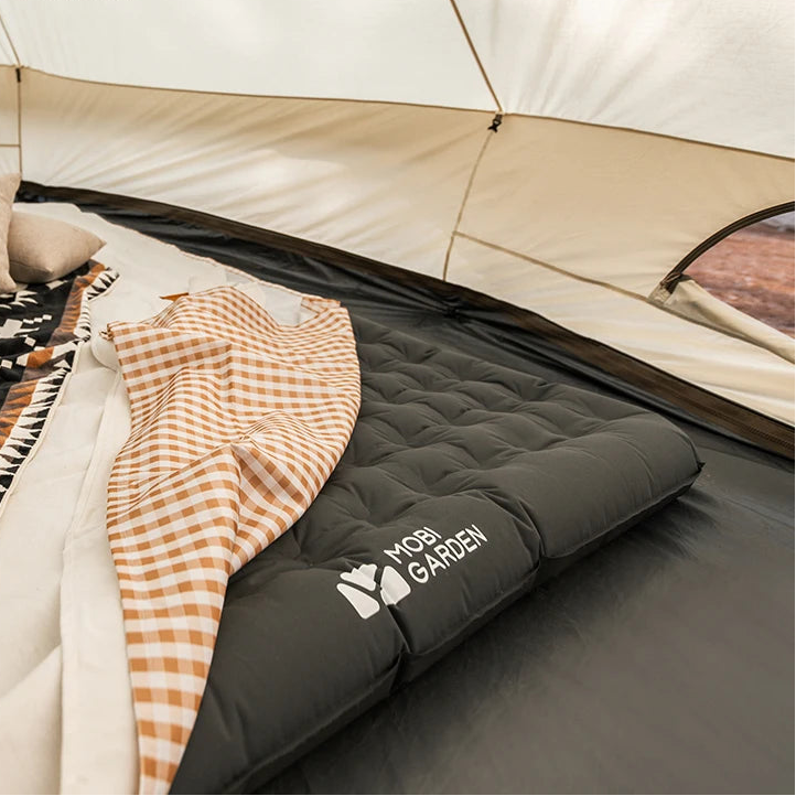 Inflatable mattress set up inside camping tent with bedding