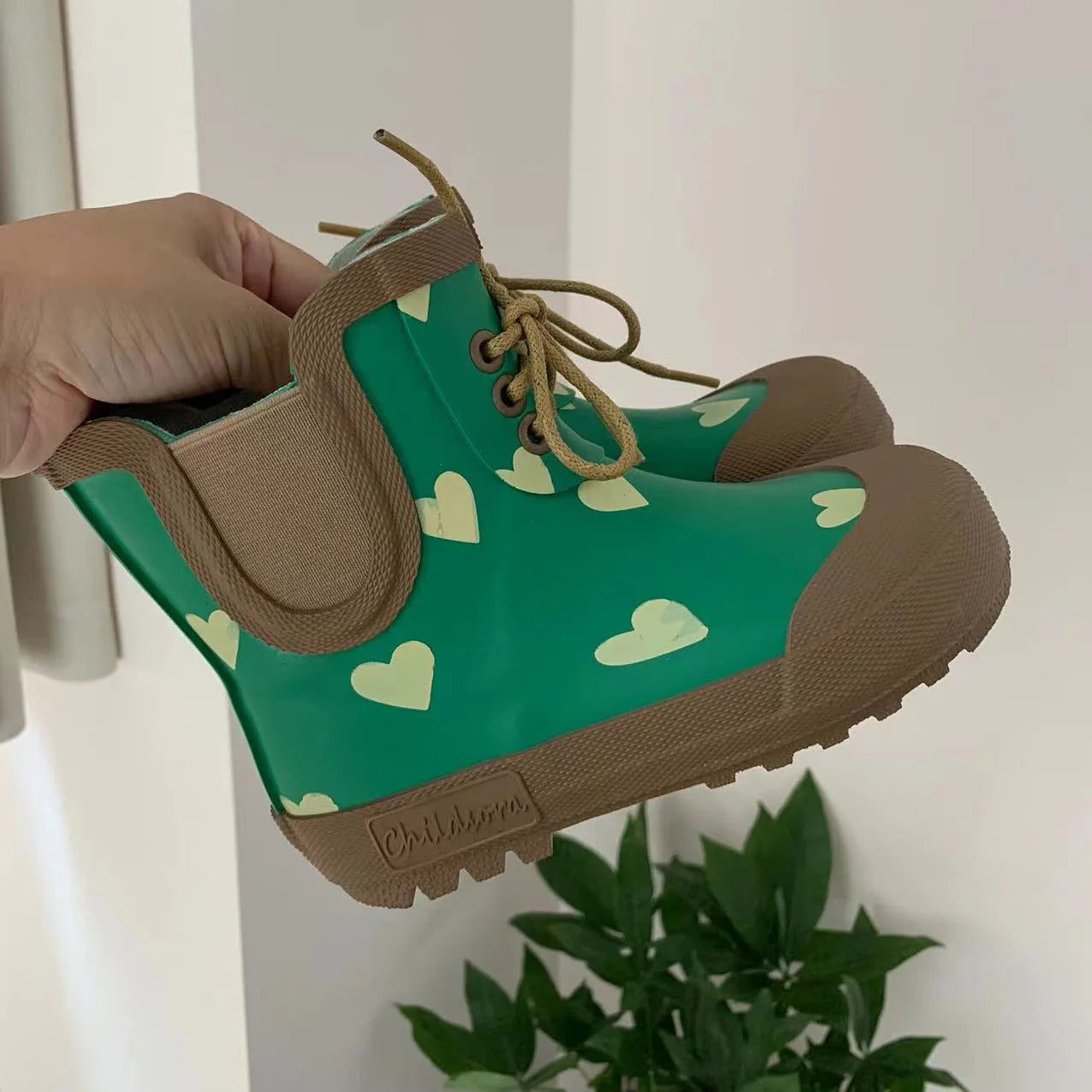 Angled view of green lace up kids rain boots with grip sole