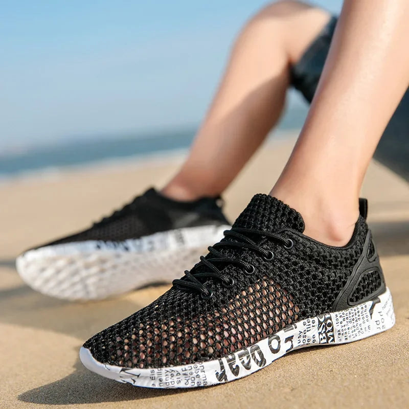 Men’s black mesh water shoes worn on beach surface