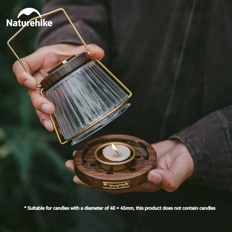 Close-up of NATUREHIKE candle lantern with person opening base to insert tealight for outdoor use