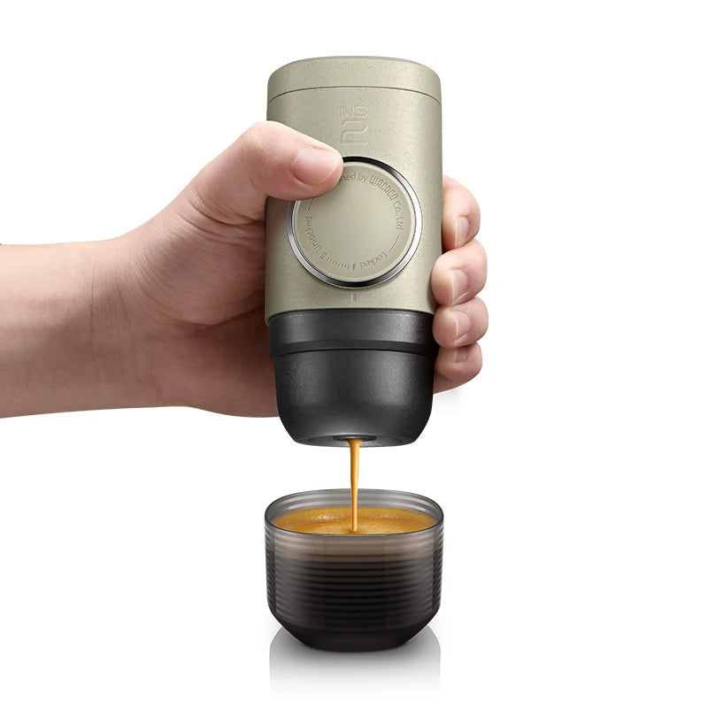 Hand pressing the Minipresso NS2 portable espresso maker pouring fresh espresso into cup for rich coffee anywhere