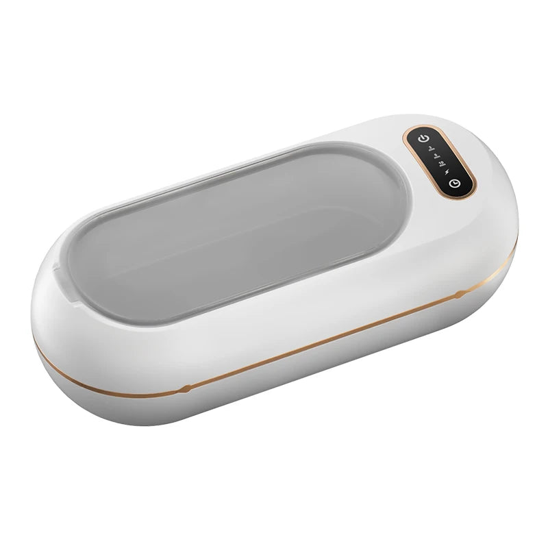 Portable ultrasonic cleaner with lid beside makeup brushes and accessories showing wireless design and portability