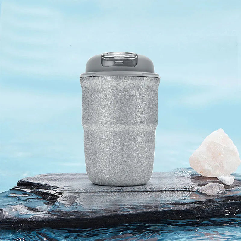 Silver titanium flask photographed outdoors on stone surface showing rugged durability and sleek design