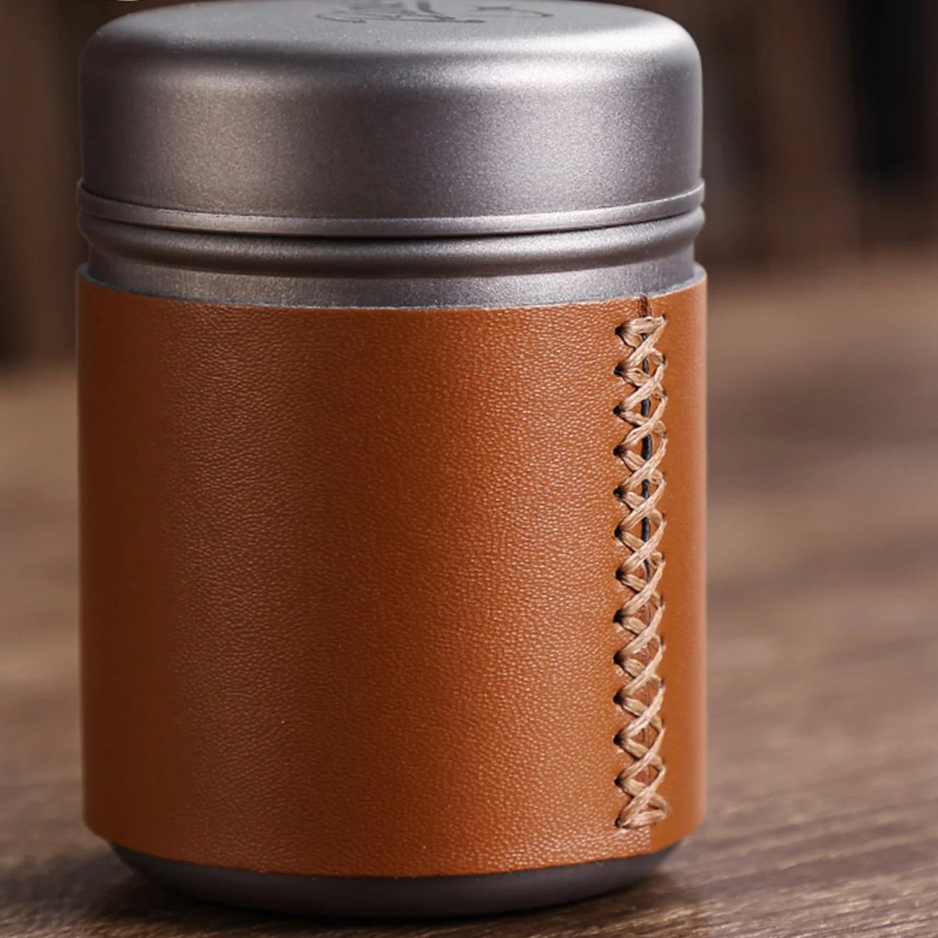 Close-up of titanium coffee canister showing fine stitched leather sleeve and airtight lid design