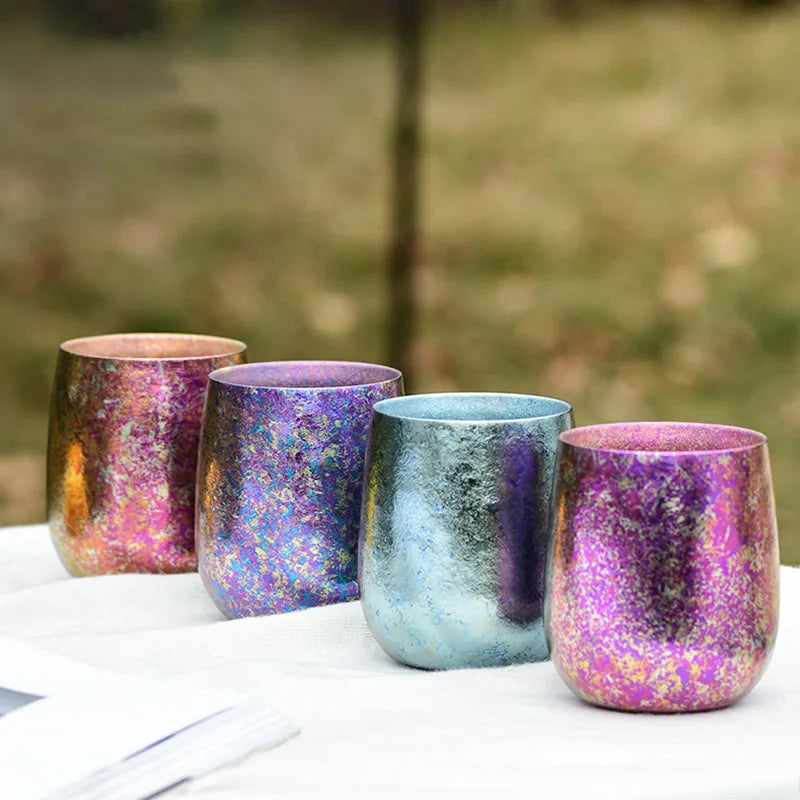 Multicolour titanium cups displayed outdoors on table