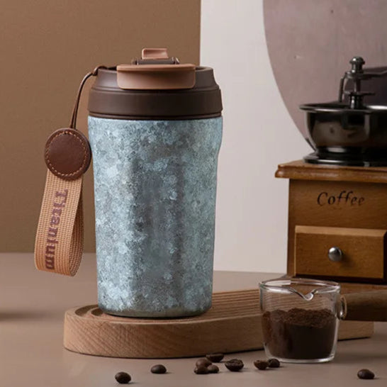 Titanium thermos cup featuring brown leather Titanium tag and textured blue finish on modern grey background