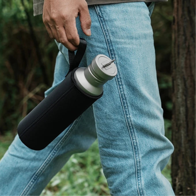 Titanium water bottle carried by hand outdoors