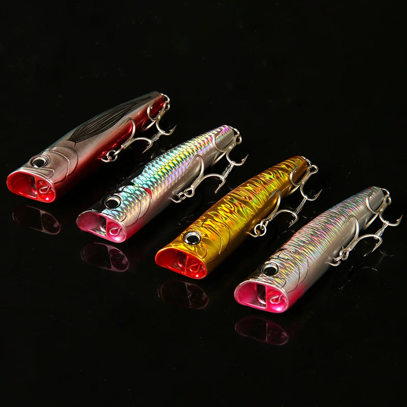 Multiple topwater popper fishing lures shown together on dark background