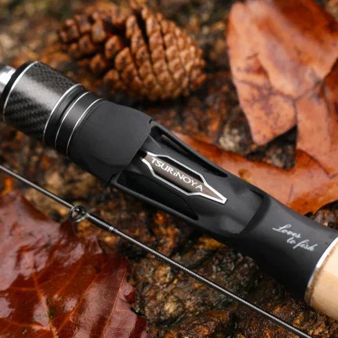 Close-up of TSURINOYA reel seat showing carbon and cork handle detail with aluminium locking hood