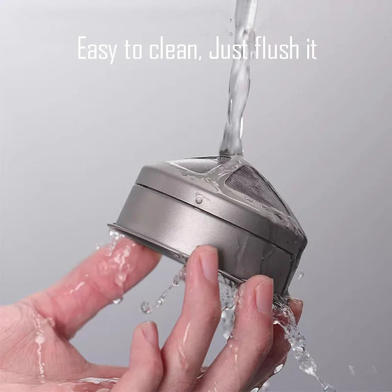 Reusable titanium coffee filter being rinsed under running water highlighting easy-clean design